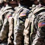 Soldiers in formation wearing camouflage and American flag patches