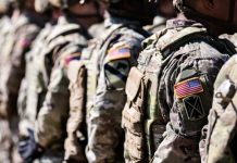 Soldiers in formation wearing camouflage and American flag patches