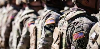 Soldiers in formation wearing camouflage and American flag patches