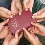Bible held by many people
