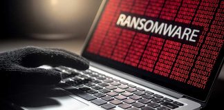 Gloved hand on laptop with ransomware screen.
