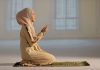 Woman praying indoors on a prayer mat
