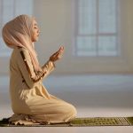 Woman praying indoors on a prayer mat