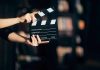 Hands holding a film clapperboard against a dark background