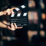 Hands holding a film clapperboard against a dark background