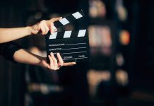 Hands holding a film clapperboard against a dark background