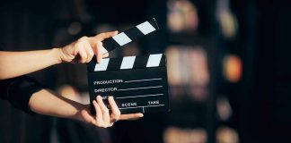 Hands holding a film clapperboard against a dark background