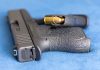 Handgun on blue fabric with visible bullet cartridge