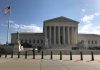 Supreme Court building with flag and people outside