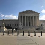Supreme Court building with flag and people outside