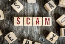 Wooden blocks spell SCAM on a rustic surface