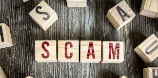 Wooden blocks spell SCAM on a rustic surface