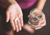 Person holding pill and glass of water