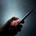 Hand holding a smartphone in dim light