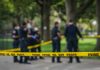 Police officers standing behind crime scene tape outside