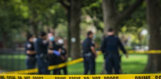 Police officers standing behind crime scene tape outside