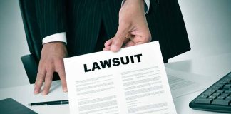 Person holding a document titled "LAWSUIT" in office.