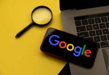 Magnifying glass laptop and smartphone displaying Googles logo
