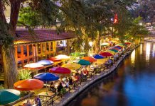 Outdoor riverside restaurant with colorful umbrellas and evening lights
