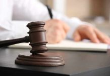 Judges gavel on desk with person writing