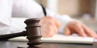 Judges gavel on desk with person writing