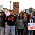 Group of people holding various protest signs outdoors
