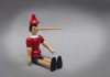 Wooden toy figure with long nose sitting