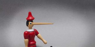 Wooden toy figure with long nose sitting