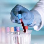 Gloved hand holding a blood sample test tube