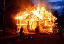 House engulfed in flames with firefighters present
