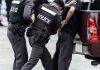 Police officers arresting a handcuffed person