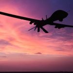 Silhouette of drone flying against colorful sunset sky