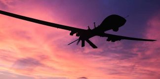 Silhouette of drone flying against colorful sunset sky