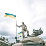 Soldier on tank holding Ukrainian flag