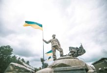 Soldier on tank holding Ukrainian flag