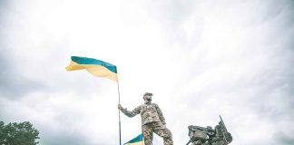 Soldier on tank holding Ukrainian flag