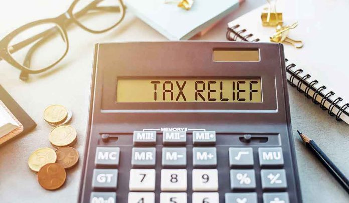 1908079453 Calculator display reads "TAX RELIEF" amidst coins and glasses.