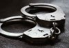 Close up of metal handcuffs on a dark surface