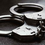 Close up of metal handcuffs on a dark surface