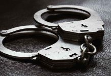 Close up of metal handcuffs on a dark surface