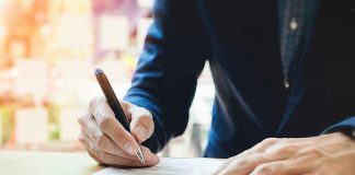 Person signing a document with a pen