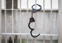 Handcuffs hanging on white metal bars