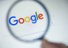 Google logo viewed through a magnifying glass.