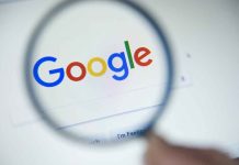 Google logo viewed through a magnifying glass.