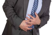Businessman in a suit holding his stomach appearing to be in discomfort