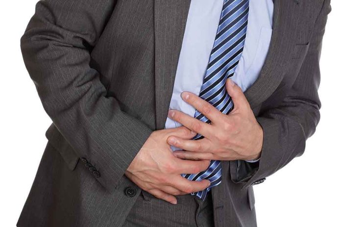 shutterstock_101302762.jpg Businessman in a suit holding his stomach appearing to be in discomfort