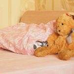 A cozy bedroom scene featuring a stuffed bunny and pink bedding