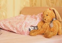 A cozy bedroom scene featuring a stuffed bunny and pink bedding