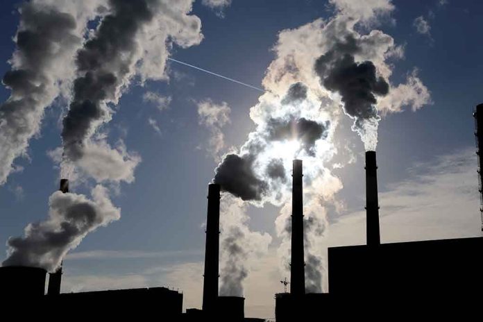 shutterstock_226073734.jpg Silhouetted smokestacks emitting smoke against a cloudy sky with sunlight