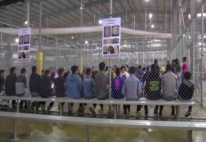 People sitting on benches inside a fenced facility